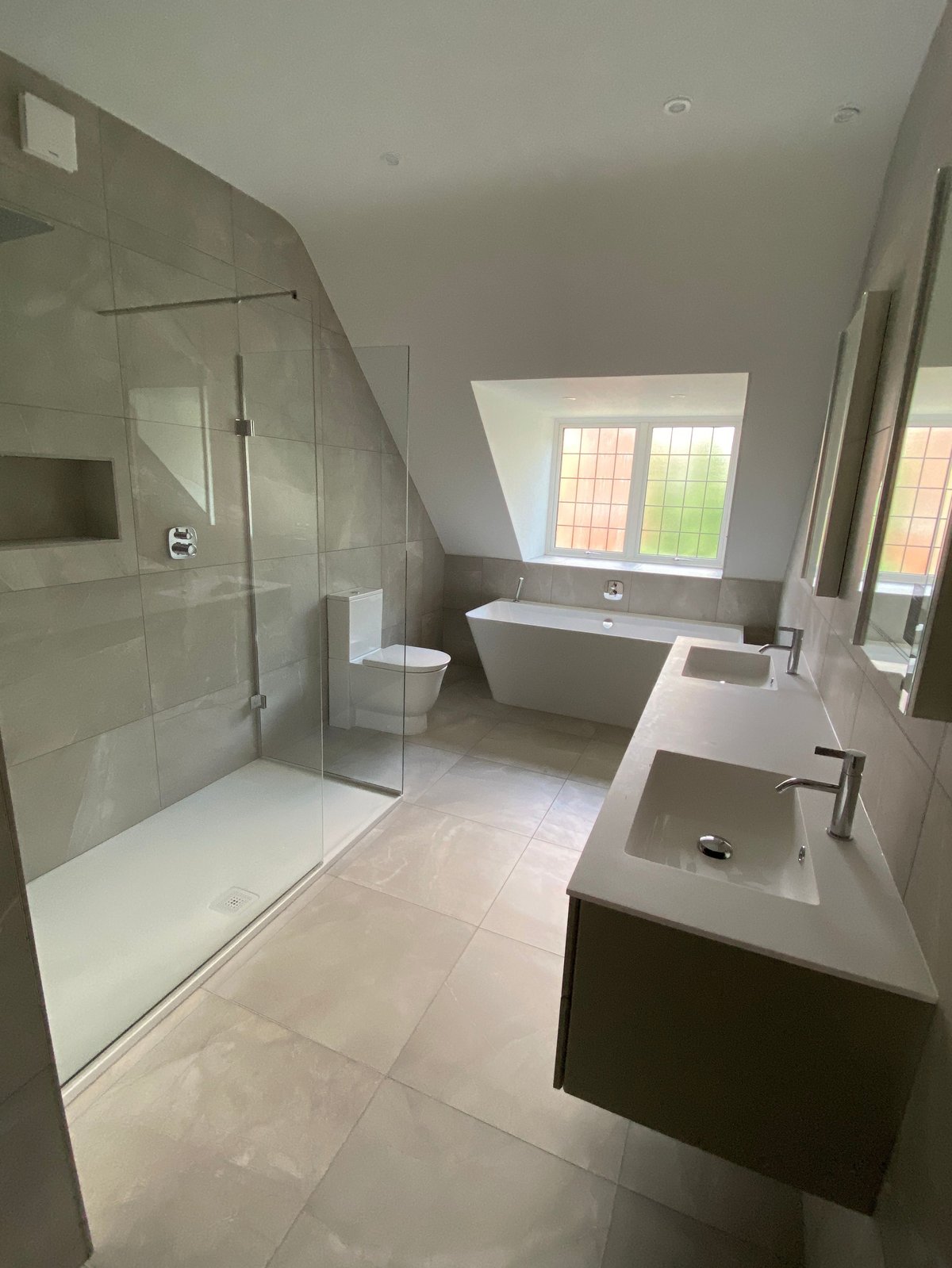 Modern bathroom with large walk-in shower, freestanding tub, double sink vanity, and windows overlooking garden